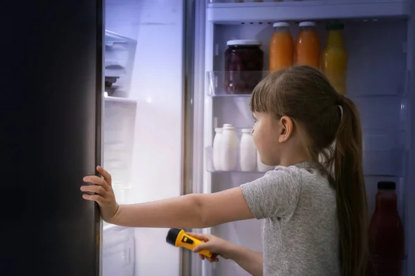 Cute little girl choosing food in fridge at night — Stock Photo, Image