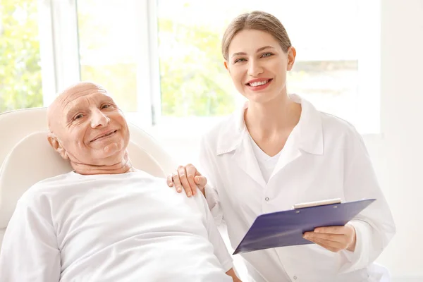 Elderly man with doctor in modern clinic — Stock Photo, Image