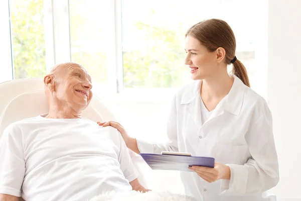 Elderly man with doctor in modern clinic — Stock Photo, Image