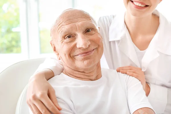 Elderly man with doctor in modern clinic — Stock Photo, Image