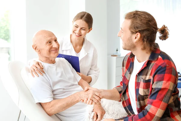 Young man visiting his elderly father in modern clinic — Stock Photo, Image