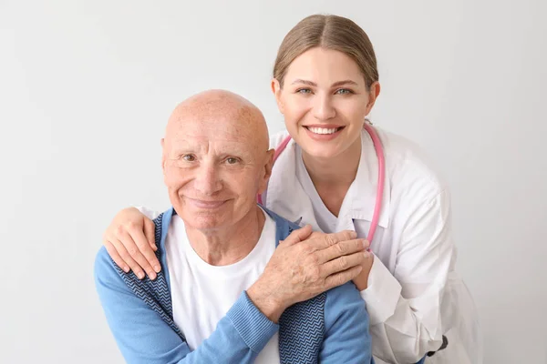 Älterer Mann mit Arzt vor hellem Hintergrund — Stockfoto