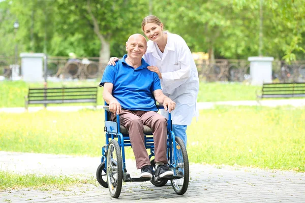 Elderly man with caregiver in park — Stock Photo, Image