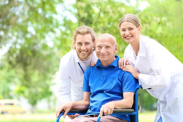 Elderly man with caregivers in park — Stock Photo, Image