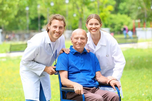 Elderly man with caregivers in park — Stock Photo, Image