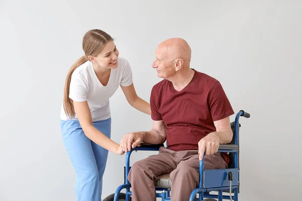 Elderly man with his daughter on light background — Stock Photo, Image