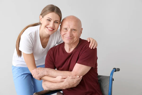 Elderly man with his daughter on light background — Stock Photo, Image