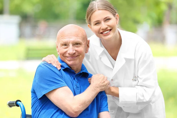 Elderly man with caregiver in park — Stock Photo, Image