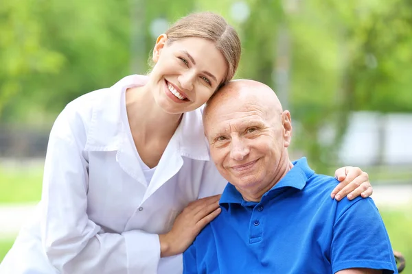 Elderly man with caregiver in park — Stock Photo, Image