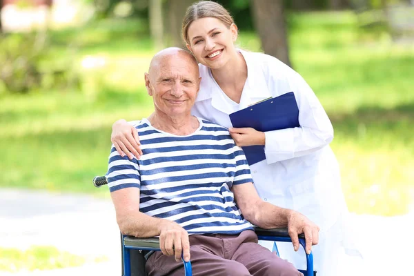 Elderly man with caregiver in park — Stock Photo, Image