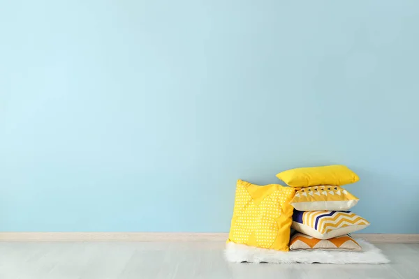 Soft pillows on floor near color wall — Stock Photo, Image