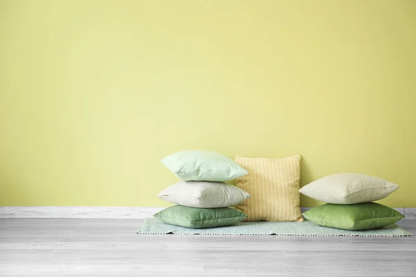 Soft pillows on floor near color wall — Stock Photo, Image