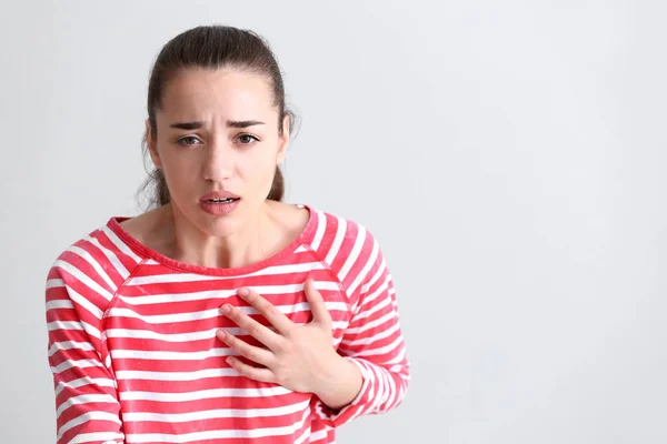 Junge Frau erleidet Herzinfarkt vor hellem Hintergrund — Stockfoto