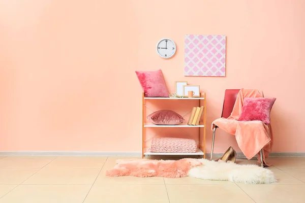 Chair and shelf unit with decor and soft pillows near color wall — Stock Photo, Image