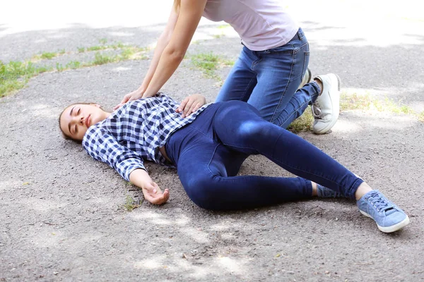 Passador feminino fazendo RCP em mulher inconsciente ao ar livre — Fotografia de Stock