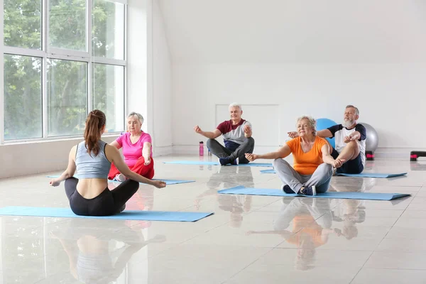 Anziani che praticano yoga con istruttore in palestra — Foto Stock