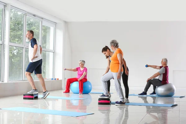 Elderly people training with instructor in gym — Stock Photo, Image