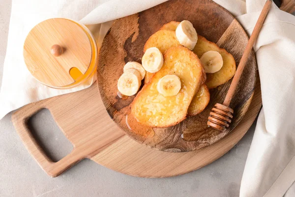 Plate with tasty French toasts, honey and banana on grey background — Stock Photo, Image