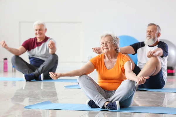 Ältere Menschen praktizieren Yoga im Fitnessstudio — Stockfoto