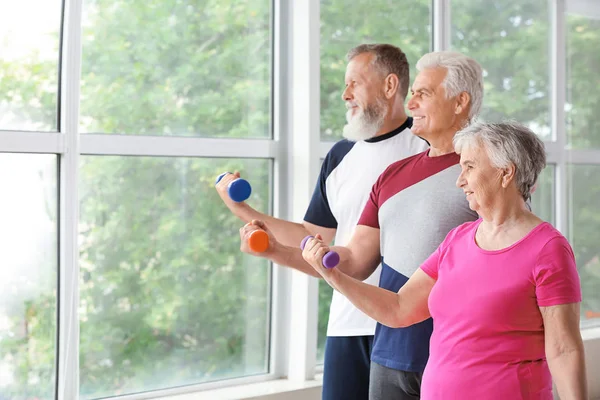 Starsi ludzie trenują z hantlami w siłowni — Zdjęcie stockowe