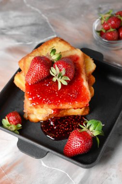 Gri arka planda lezzetli Fransız tost ve çilek ile Kızartma tavası