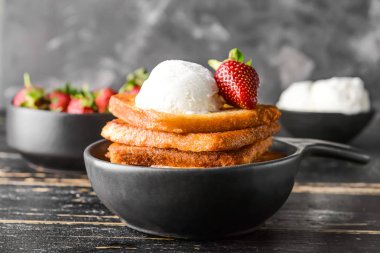 Koyu masaüzerinde lezzetli Fransız tost, dondurma ve çilek ile Kızartma tavası