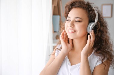 Güzel genç kadın evde pencere yakınındaki müzik dinlemek
