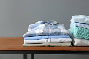 Gri arka plana karşı masaya yığılmış giysiler