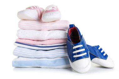 Beyaz arka planda bebek kıyafetleri ve ayakkabıları yığını