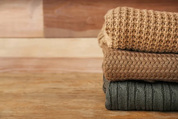 Stack of warm clothes on wooden table — Stock Photo, Image