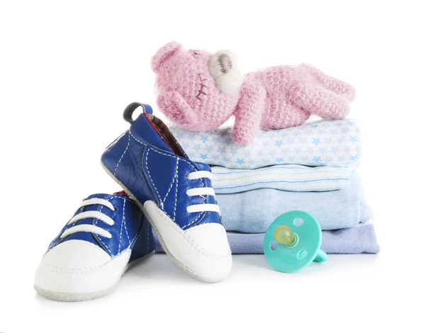 Pilha de roupas de bebê, urso de brinquedo e chupeta no fundo branco — Fotografia de Stock