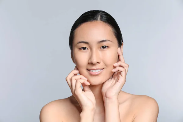 Mulher asiática antes de aplicar maquiagem no fundo cinza — Fotografia de Stock