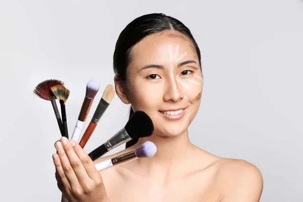 亚洲妇女与轮廓化妆和刷子在光背景 — 图库照片