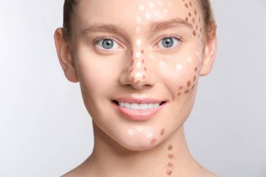 Hafif arka planda makyajlı genç bir kadın.