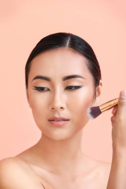 Renkli arka planda güzel makyaj ve fırça ile Asyalı kadın