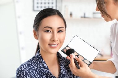 Makyaj sanatçısı güzellik salonunda Asya modeli ile çalışıyor