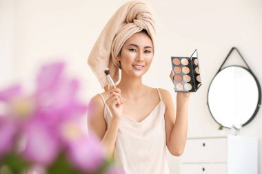 Asyalı kadın evde kontur makyaj uygulayarak