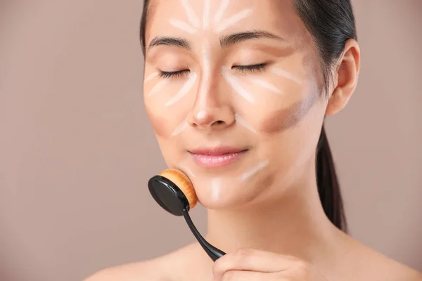 Mujer asiática con maquillaje contorneante sobre fondo de color —  Fotos de Stock