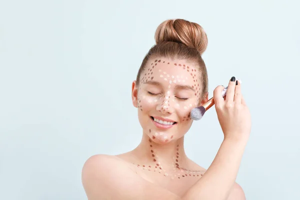 Jonge vrouw met contouring make-up en borstel op lichte achtergrond — Stockfoto