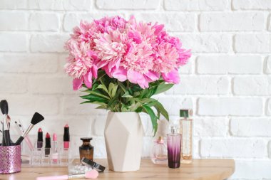 Odada masada güzel şakayık çiçekler ve kozmetik ile Vazo