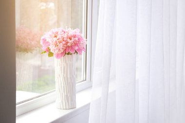 Pencere pervazında güzel şakayık çiçekleri olan vazo