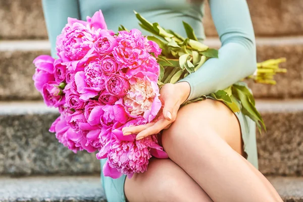Woman with bouquet of beautiful peony flowers sitting on stairs outdoors, closeup — Stock Photo, Image