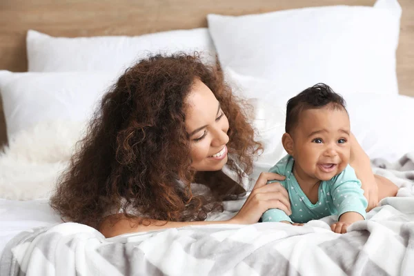 Happy African-American mother with cute little baby in bedroom — Stock Photo, Image