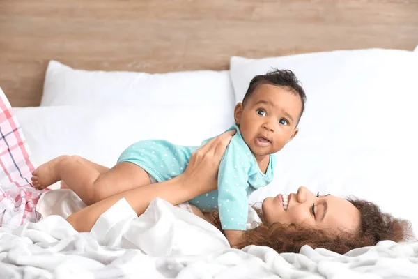 Boldog afro-amerikai anya aranyos kis baba a hálószobában — Stock Fotó