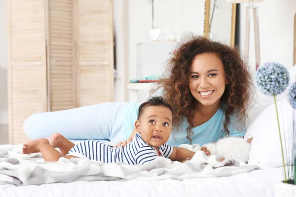 Happy African-American mother with cute little baby in bedroom — Stock Photo, Image