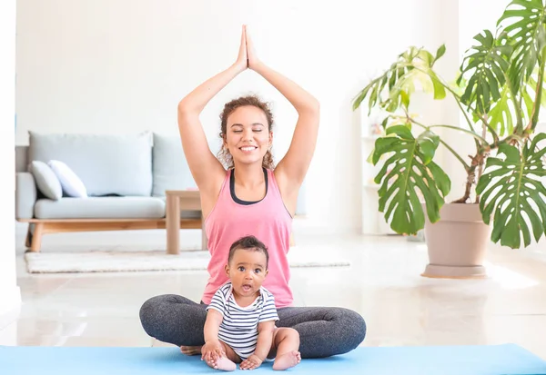 African-American woman with cute little baby practicing yoga at home — Stock Photo, Image