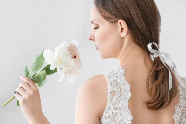 Jonge bruid met mooie pioen op lichte achtergrond — Stockfoto