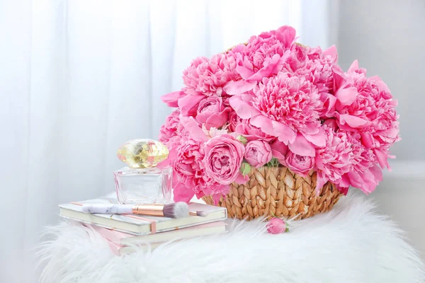 Lindas peônias com livros, frascos de perfume e pincéis de maquiagem no quarto — Fotografia de Stock