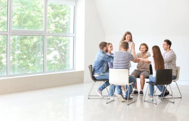 Genç insanlar grup terapisi oturumunda el tutuyorlar