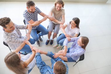 Genç insanlar grup terapisi oturumunda el tutuyorlar